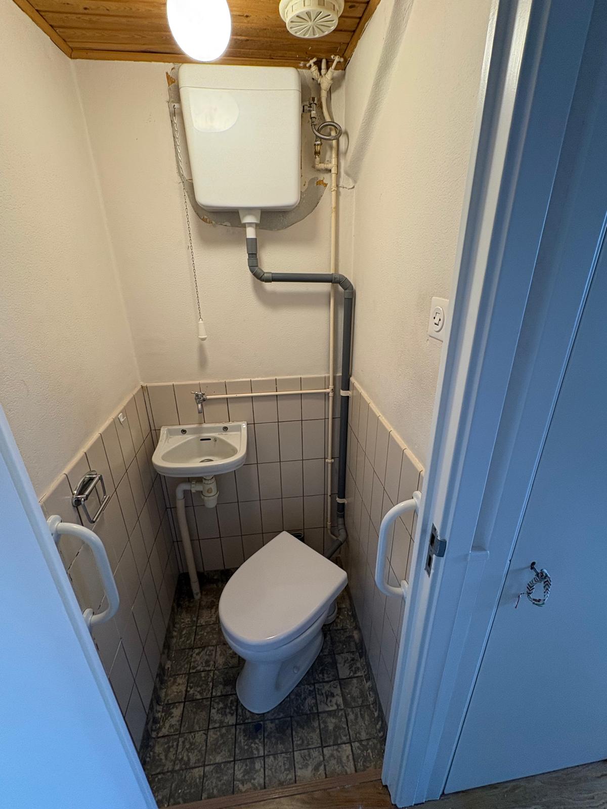 Toilet en zichtbare afvoerinstallatie in een toiletruimte